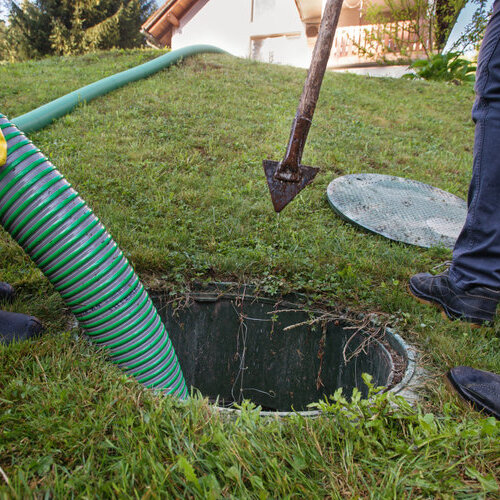 workers using a hose to drain a septic tank