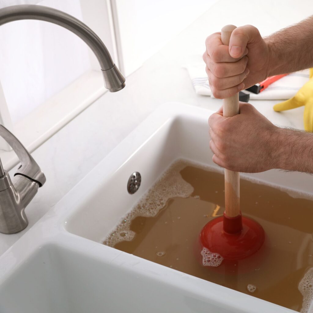 man plunging kitchen sink