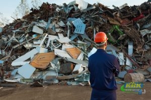 Worker stands in front of pile of recyclable materials